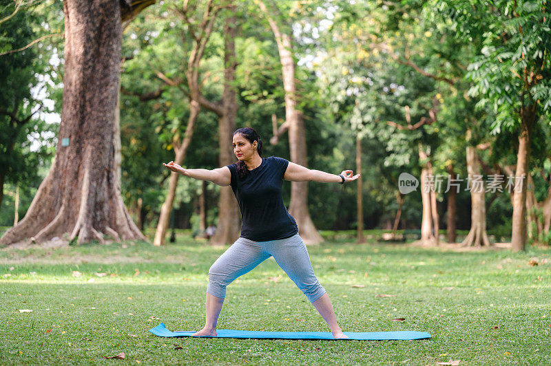 亚洲/印度女性在公园表演瑜伽体式，战士两种练习或Virabhadrasana II。